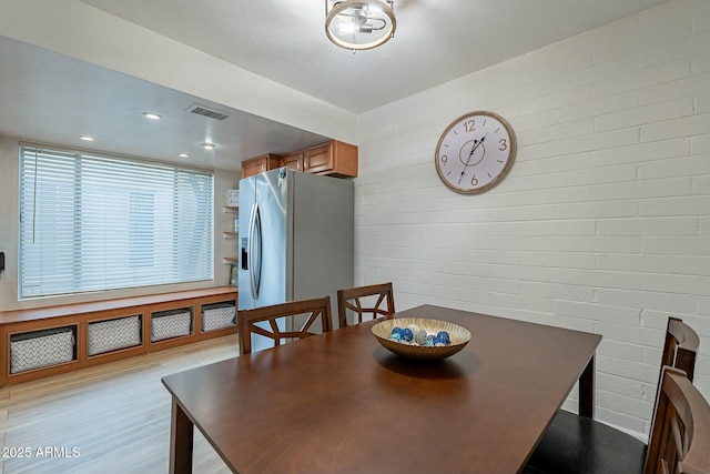 dining area featuring light hardwood / wood-style floors and brick wall