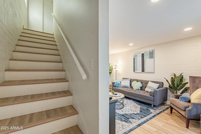 stairway featuring hardwood / wood-style floors and brick wall