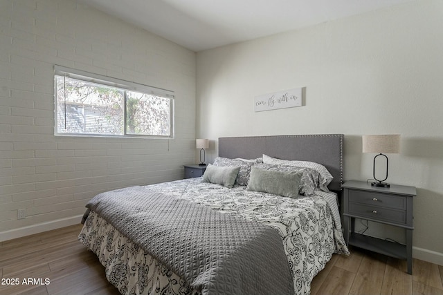 bedroom featuring hardwood / wood-style flooring and brick wall