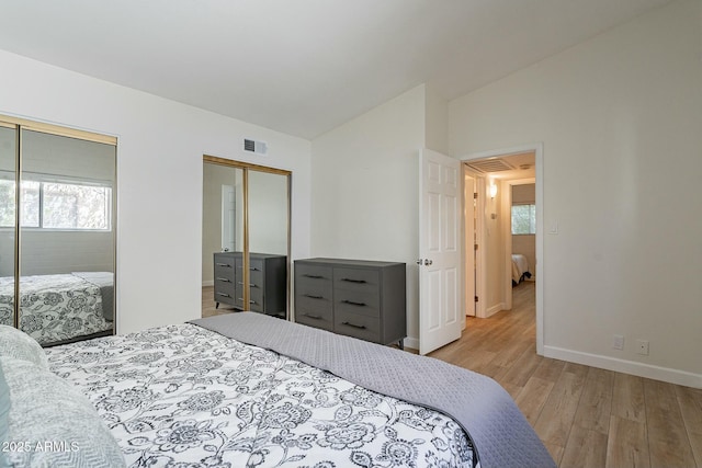 bedroom featuring a closet, vaulted ceiling, light hardwood / wood-style flooring, and multiple windows