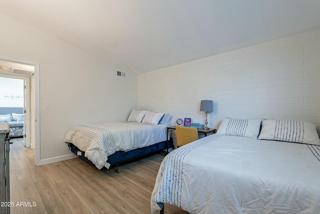 bedroom with vaulted ceiling and light wood-type flooring