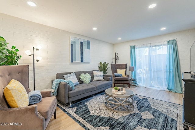 living room featuring hardwood / wood-style flooring and brick wall