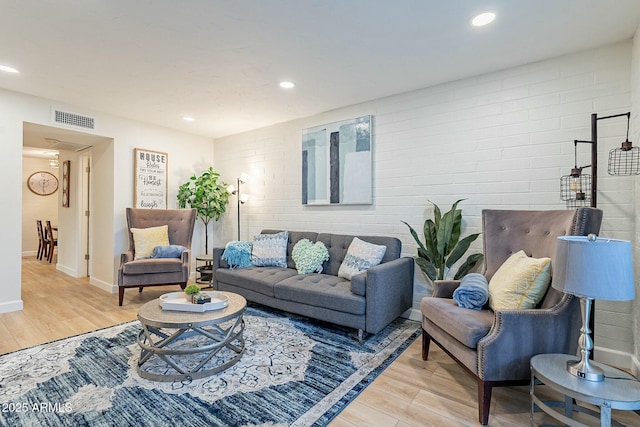 living room featuring light wood-type flooring and brick wall