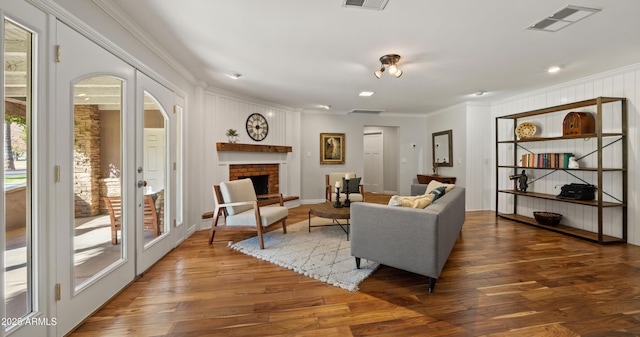 living room featuring french doors, a brick fireplace, dark hardwood / wood-style flooring, and ornamental molding