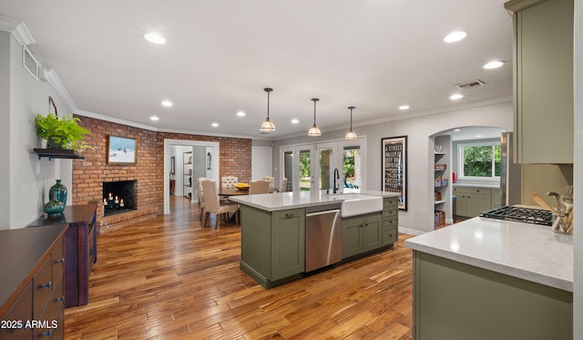 kitchen featuring stainless steel dishwasher, sink, hanging light fixtures, a healthy amount of sunlight, and an island with sink