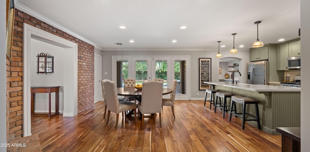 dining area with brick wall, dark hardwood / wood-style floors, crown molding, and french doors