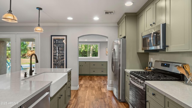 kitchen with stainless steel appliances, a healthy amount of sunlight, decorative light fixtures, ornamental molding, and sink