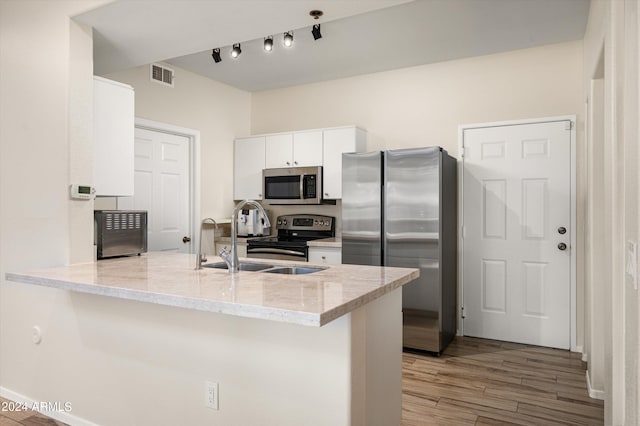 kitchen featuring appliances with stainless steel finishes, white cabinetry, light stone counters, kitchen peninsula, and light wood-type flooring