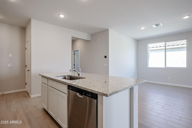 kitchen featuring white cabinetry, a kitchen island with sink, light stone counters, stainless steel dishwasher, and light wood-type flooring