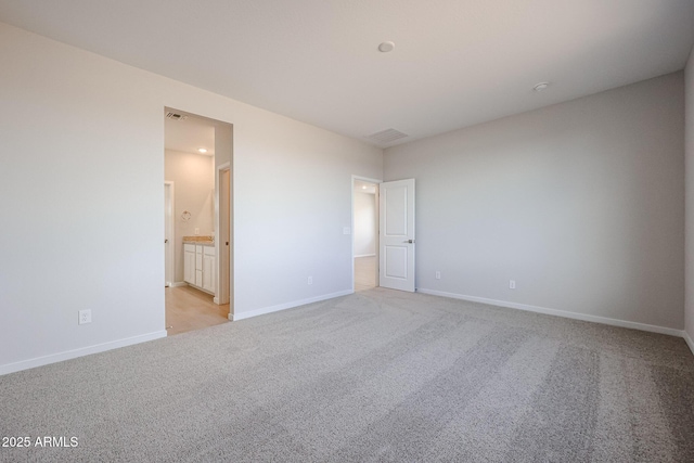 unfurnished bedroom featuring connected bathroom and light carpet