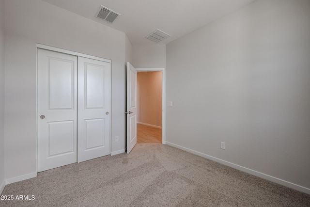 unfurnished bedroom featuring light colored carpet and a closet