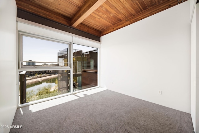 carpeted empty room featuring wooden ceiling, a water view, and beam ceiling