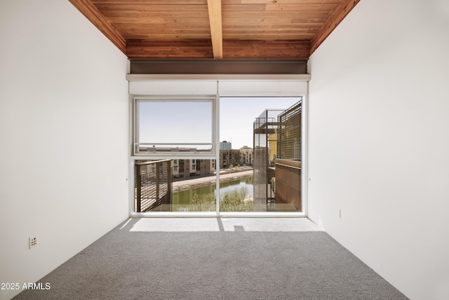 carpeted spare room featuring beam ceiling, wood ceiling, and a water view