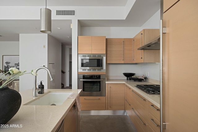 kitchen with visible vents, under cabinet range hood, light stone counters, stainless steel appliances, and a sink