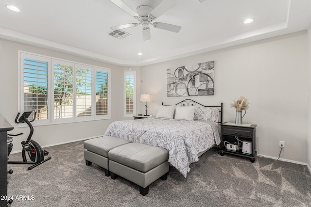 carpeted bedroom featuring ceiling fan and a tray ceiling