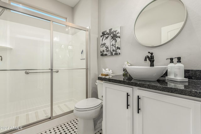 bathroom featuring tile patterned flooring, vanity, toilet, and a shower with door