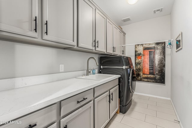 laundry room with cabinets, washing machine and dryer, sink, and light tile patterned floors