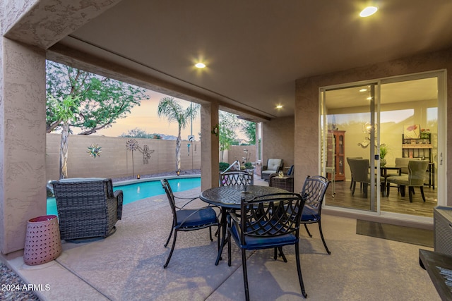 patio terrace at dusk with a fenced in pool