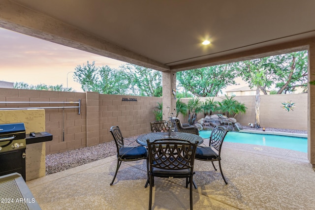 patio terrace at dusk with a fenced in pool