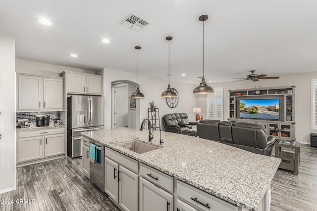 kitchen featuring a center island with sink, appliances with stainless steel finishes, sink, dark wood-type flooring, and ceiling fan