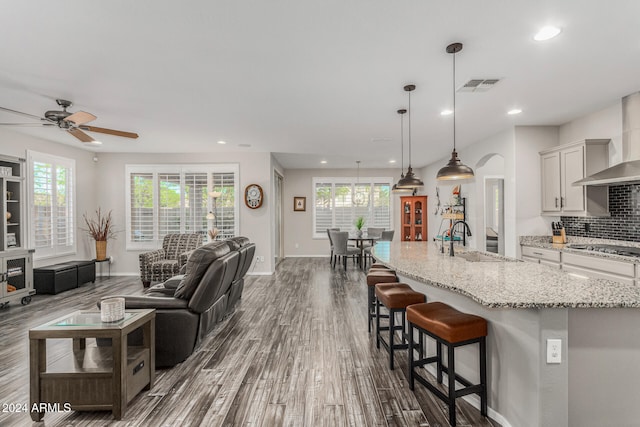 kitchen featuring sink, backsplash, hanging light fixtures, a spacious island, and dark wood-type flooring