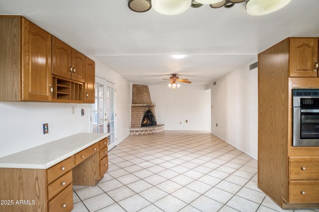 2001 Golf Links Rd, Sierra Vista, AZ 85635 - kitchen with a ceiling fan, stainless steel oven, light countertops, a fireplace, and brown cabinets