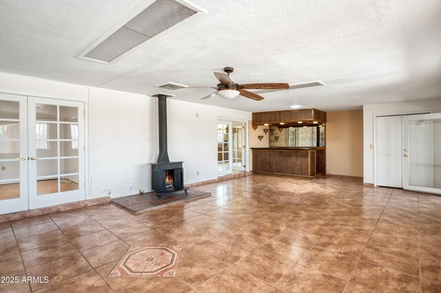 2001 Golf Links Rd, Sierra Vista, AZ 85635 - unfurnished living room featuring french doors, a wood stove, a ceiling fan, and a textured ceiling