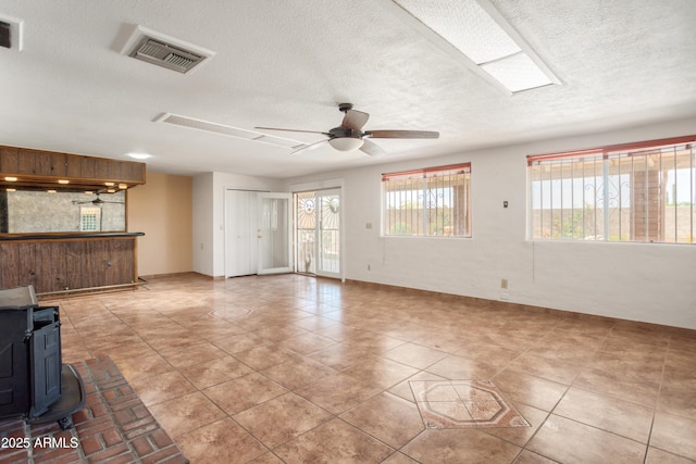 2001 Golf Links Rd, Sierra Vista, AZ 85635 - unfurnished living room with a textured ceiling, a wood stove, baseboards, ceiling fan, and tile patterned flooring