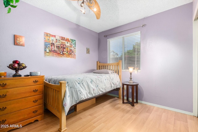 bedroom featuring ceiling fan, a textured ceiling, and light wood-type flooring