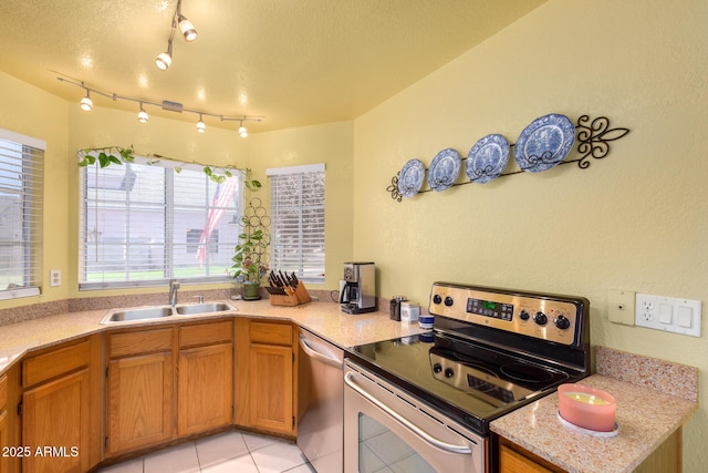 kitchen with appliances with stainless steel finishes, kitchen peninsula, sink, and a textured ceiling