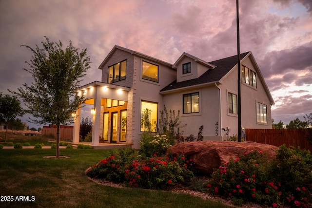 back of house featuring a yard, fence, and stucco siding