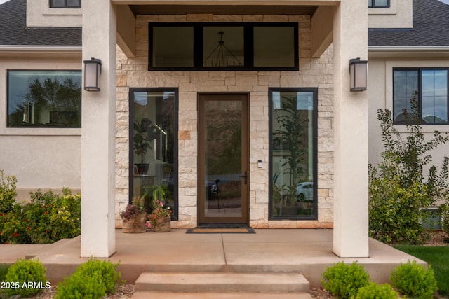 entrance to property with stone siding, stucco siding, a porch, and roof with shingles