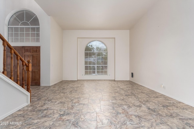 empty room featuring stairway and baseboards