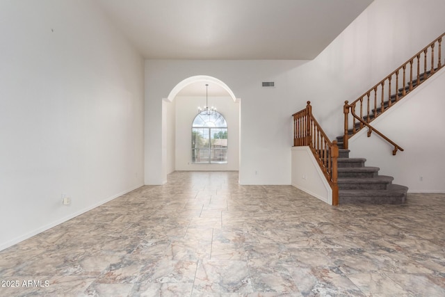 foyer with visible vents, arched walkways, baseboards, a chandelier, and stairs