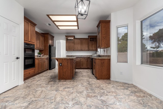 kitchen with visible vents, an inviting chandelier, a sink, black appliances, and a center island