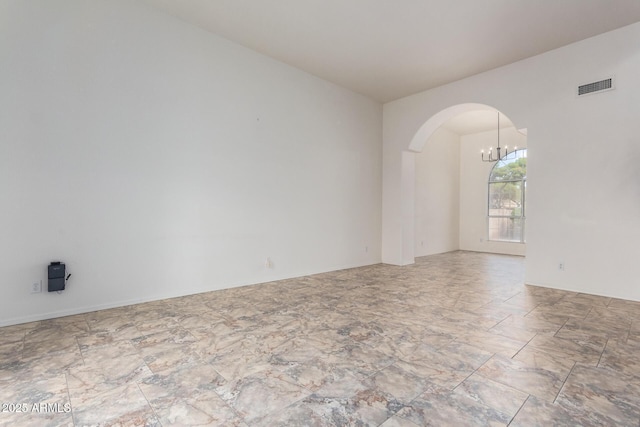 empty room featuring arched walkways, visible vents, and a notable chandelier