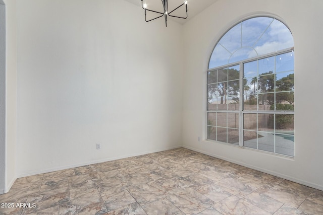 spare room featuring an inviting chandelier and baseboards