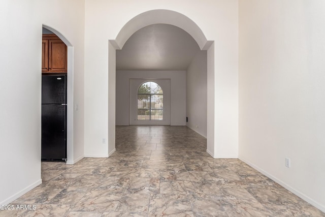 empty room with arched walkways and baseboards