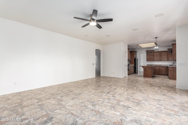 unfurnished living room with arched walkways and ceiling fan