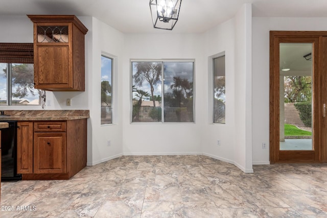 unfurnished dining area featuring baseboards and a notable chandelier