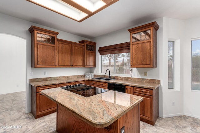 kitchen with black appliances, a kitchen island, brown cabinets, and a sink