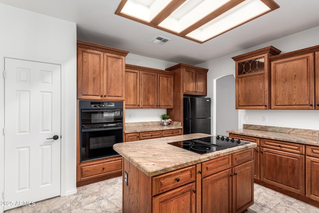 kitchen with visible vents, marble finish floor, black appliances, a kitchen island, and arched walkways