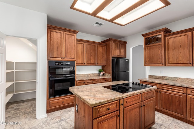 kitchen featuring visible vents, marble finish floor, black appliances, a kitchen island, and arched walkways