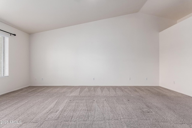 carpeted spare room with vaulted ceiling