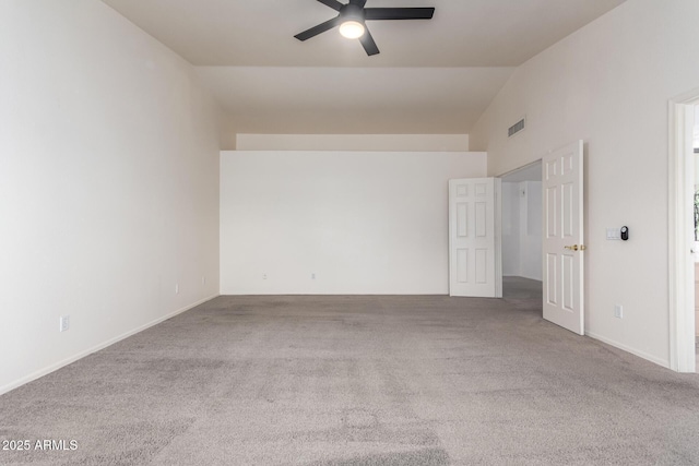 carpeted spare room featuring visible vents, a ceiling fan, and vaulted ceiling