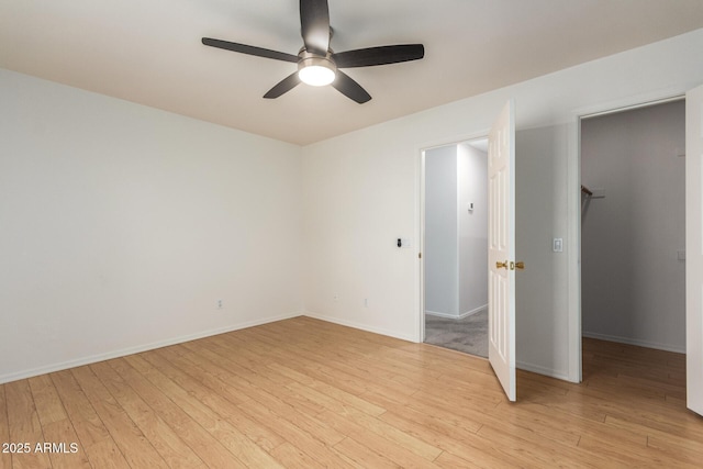 unfurnished room featuring a ceiling fan, light wood-type flooring, and baseboards