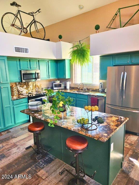 kitchen featuring a center island, light stone countertops, a breakfast bar area, and appliances with stainless steel finishes