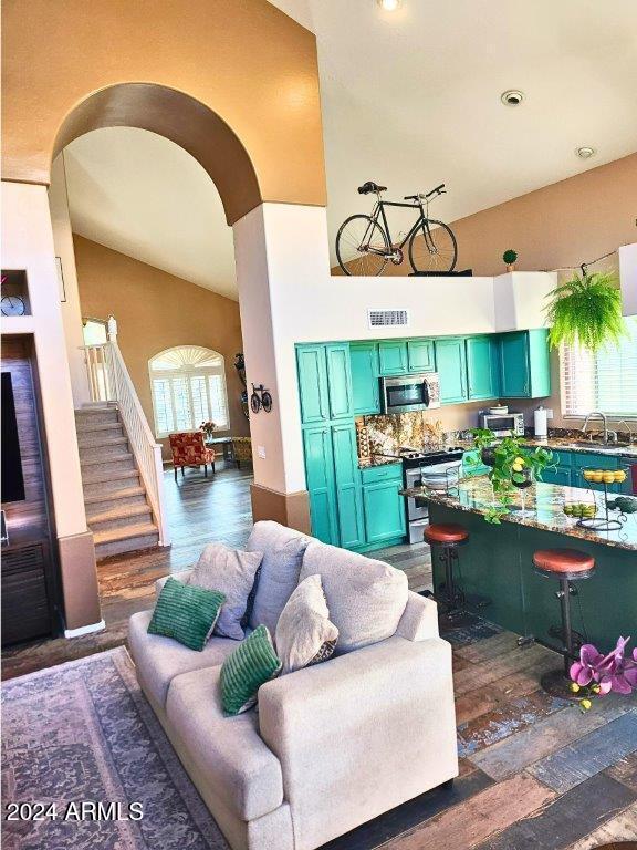 living room with dark hardwood / wood-style floors, high vaulted ceiling, a healthy amount of sunlight, and sink