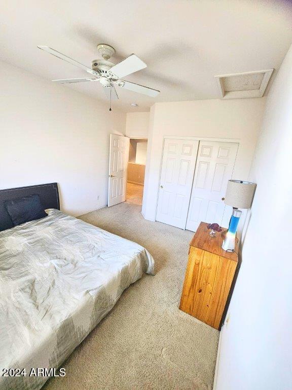 carpeted bedroom featuring ceiling fan and a closet