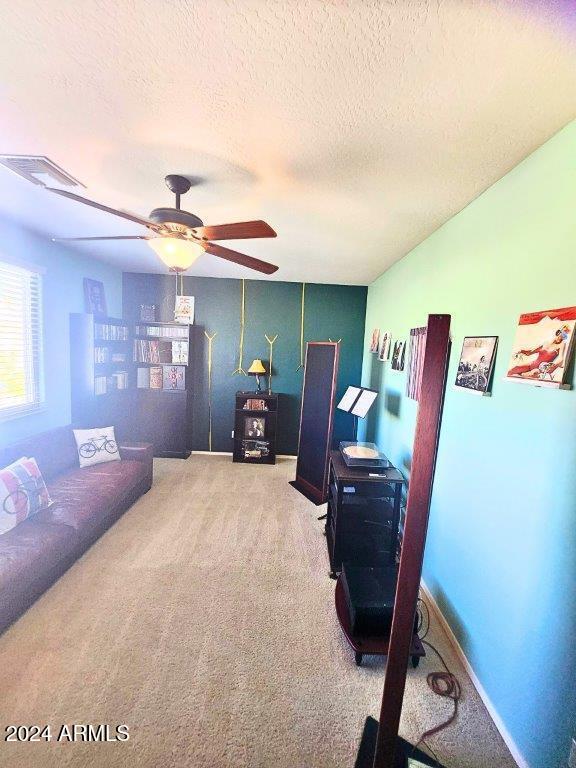 office space featuring carpet flooring, ceiling fan, and a textured ceiling